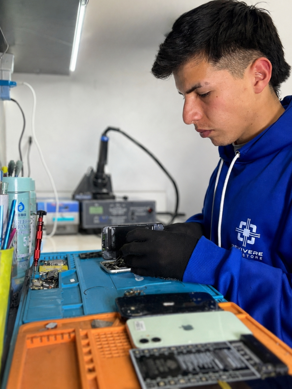 Juanda trabajando en el taller de Revivere Tech Store, realizando diagnóstico técnico sobre un iPhone